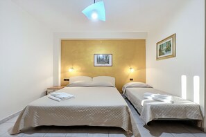 Habitación doble con dos camas, un cuadro enmarcado en la pared y una lámpara en el techo.