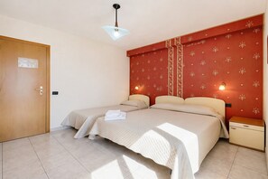 A room with two beds, a wooden door, a nightstand, and a wall with a floral pattern. - B&B Sea View with Balcony - 243- Santangelo - Pool (Monte Sant'Angelo)
