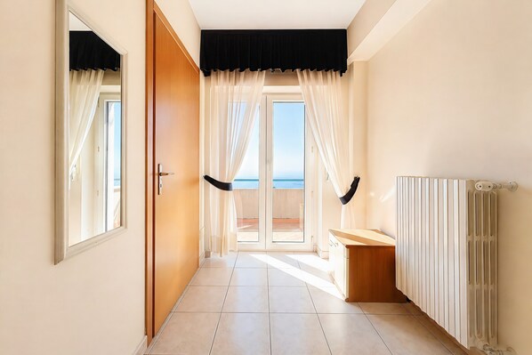 Un couloir donnant sur un balcon, avec une porte, un radiateur et une fenêtre.