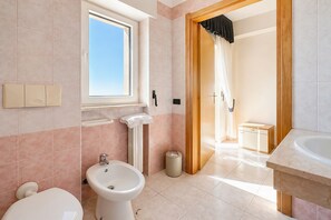 Ein Badezimmer mit Toilette, Bidet, Waschbecken und Fenster.