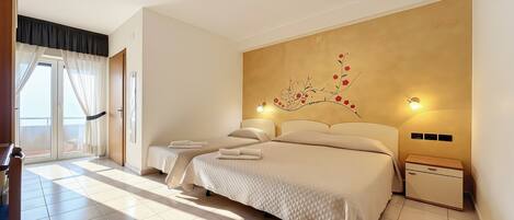 A bedroom with two beds, a window with curtains, a wall-mounted artwork, and bedside lamps.