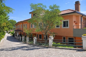 A stone-paved street leading to a two-story building with a tiled roof, a balcony, and potted plants. - Bright B&B with Sea View Balcony - 242- Santangelo - Pool (Monte Sant'Angelo)