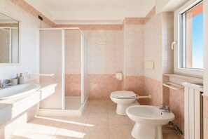 Ein Badezimmer mit Dusche, Toilette, Bidet und Waschbecken.