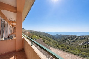 Un balcó amb vista a un paisatge amb turons i al mar.