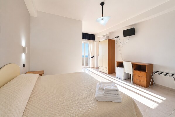 Un dormitorio con cama, escritorio, silla, armario y televisor.