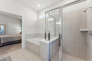 Een moderne badkamer met een glazen douchecabine, een badkuip en een grote spiegel.