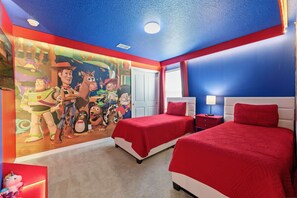 Een slaapkamer met twee bedden, een muurschildering van tekenfilmfiguren en een kleurenschema in rood en blauw.