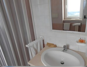 Ein Badezimmer mit Waschbecken, Spiegel, Handtuchhalter und Fenster.