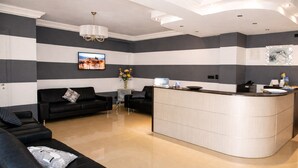 A modern hotel lobby with a black leather sofa, a curved reception desk, and a chandelier. - Bright B&B with Sea View Balcony - 244 - Santangelo - Pool (Monte Sant'Angelo)