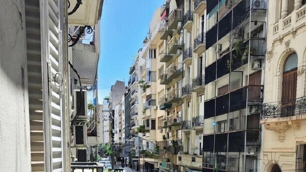 A narrow urban street with multi-story buildings, balconies, and a parked car. - Spacious 4BR· Families & Groups · Central Apartment · Recoleta (Buenos Aires)