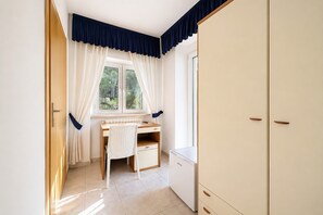 Ein Zimmer mit Schreibtisch, Stuhl und Kleiderschrank.