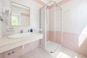 Ein Badezimmer mit Dusche, Waschbecken und Spiegel.