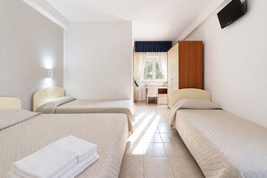Ein Hotelzimmer mit zwei Betten, einem Schreibtisch und einem Fenster mit Vorhängen.