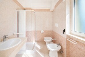 Ein Badezimmer mit Dusche, Toilette, Bidet und zwei Waschbecken.