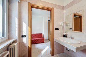 Ein Badezimmer mit einem weißen Waschbecken, einem Spiegel und einem roten Sofa im Hintergrund.