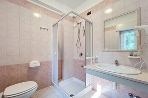Ein Badezimmer mit Dusche, Toilette, Waschbecken und Spiegel.