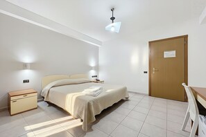 Ein Schlafzimmer mit Bett, Nachttischen, einem Schreibtisch und einer Tür.