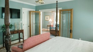 Une chambre à coucher avec un lit à baldaquin, un bureau en bois et un téléviseur fixé au mur.