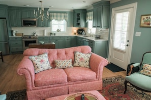 Ein gemütliches Wohnzimmer mit einem rosa Sofa, einem Holztisch und einem gemusterten Teppich.