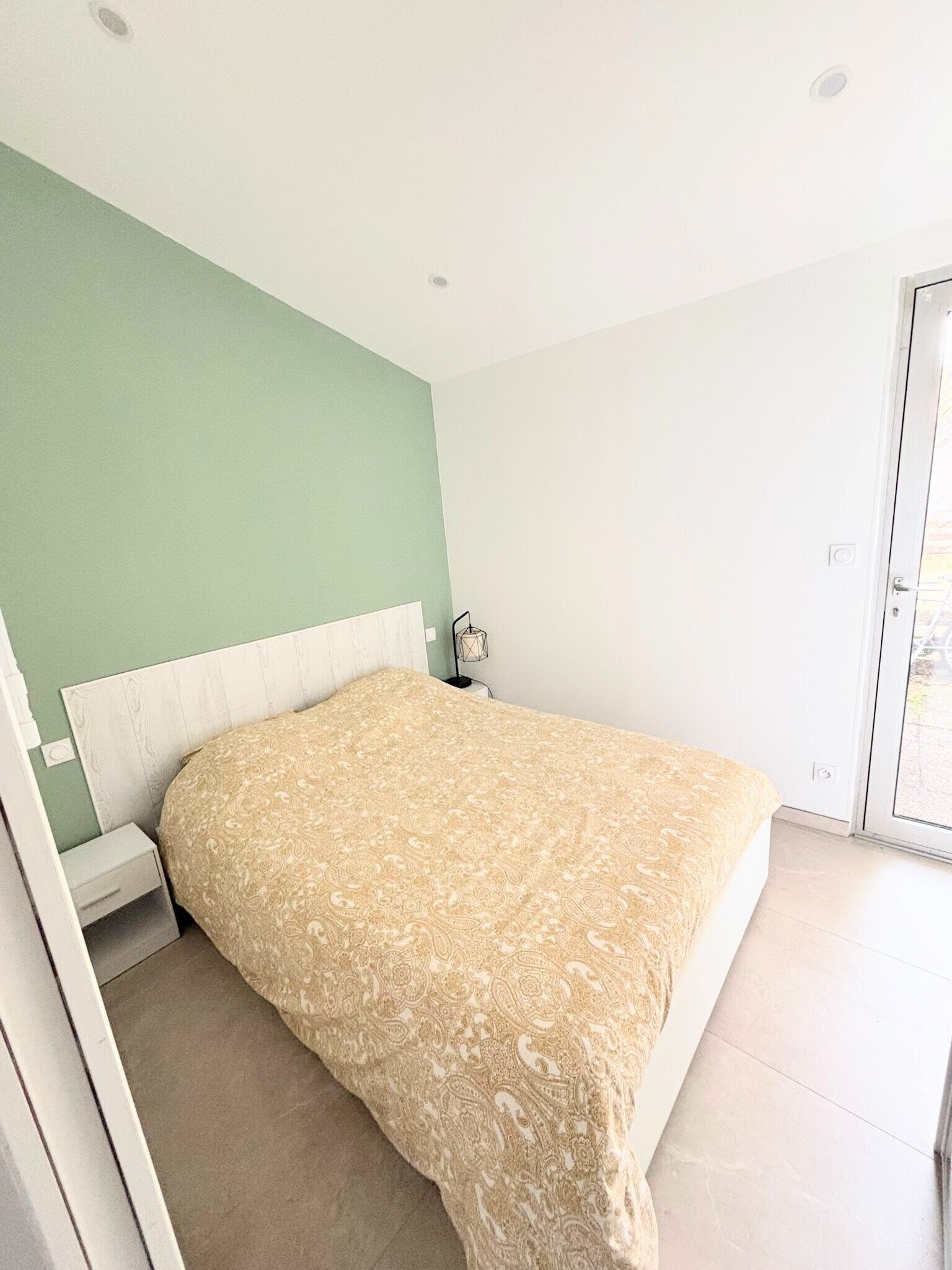 Une chambre à coucher avec un lit, une table de chevet et une fenêtre.