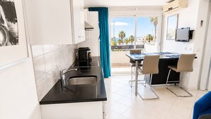 Eine moderne Küche mit Essbereich, Blick auf den Strand und einem an der Wand montierten Fernseher.