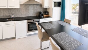 Eine moderne Küche mit weißen Schränken, einer schwarzen Arbeitsplatte und einem Essbereich mit Tisch und Stühlen.