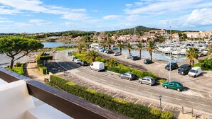 Ein Yachthafen mit Booten, ein Parkplatz und Blick auf eine Stadt mit Gebäuden und Hügeln im Hintergrund.
