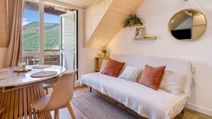 Una habitación acogedora con una cama, un espejo redondo, una planta y vistas al exterior.