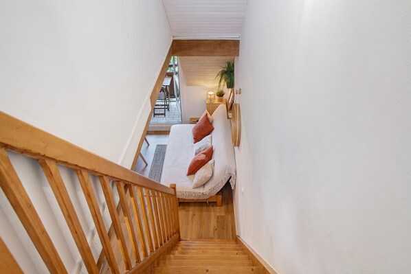 A staircase leading to a bedroom with a bed, pillows, a nightstand, and a plant.