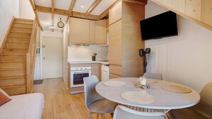 Una cocina moderna con vigas de madera, un comedor con una mesa redonda y un televisor montado en la pared.