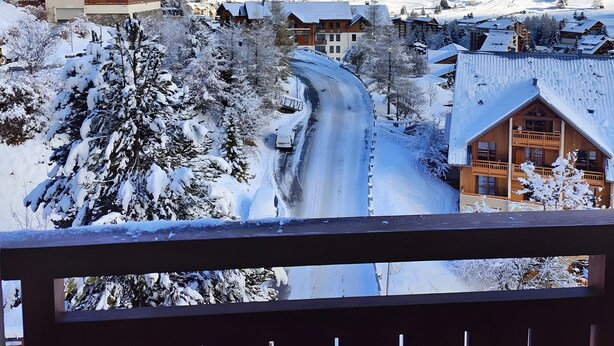 Un pueblo de montaña cubierto de nieve con casas de madera y cielo despejado.