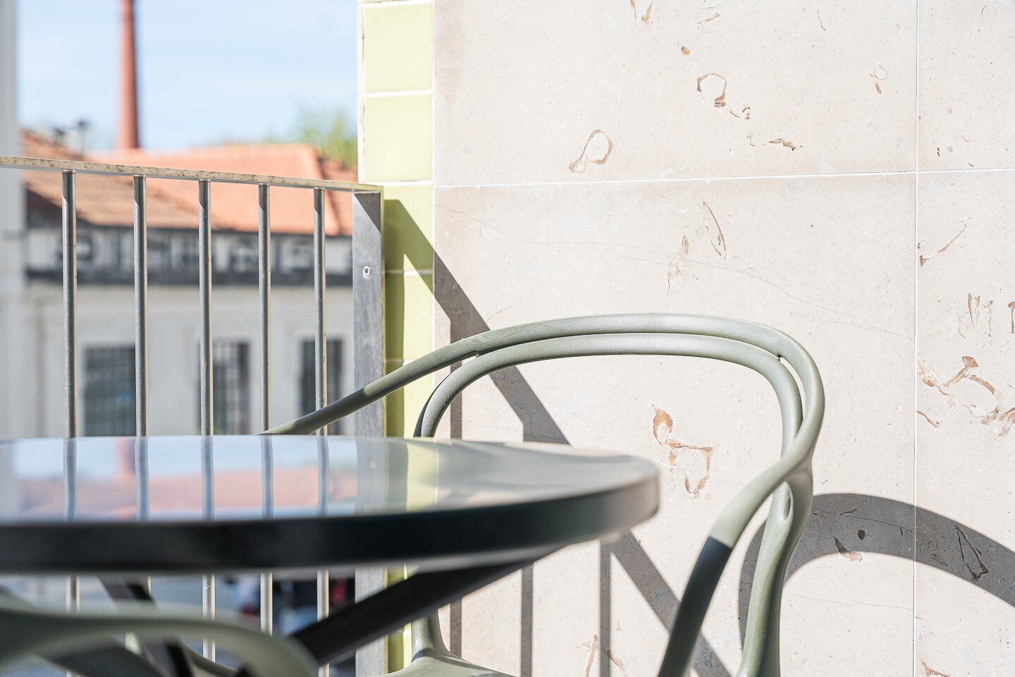 A balcony with a metal railing, a round table, and a chair.