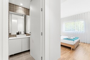 A modern bathroom with a sink, mirror, and tiled backsplash. - GuestReady - Seaside retreat - 1D (Matosinhos)