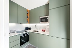 A compact kitchen with a microwave, oven, sink, and a coffee maker. - GuestReady - Seaside retreat - 1D (Matosinhos)