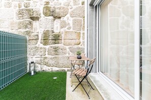 A stone wall, a small lawn, and a table with chairs. - GuestReady - Studio in Porto (Porto)
