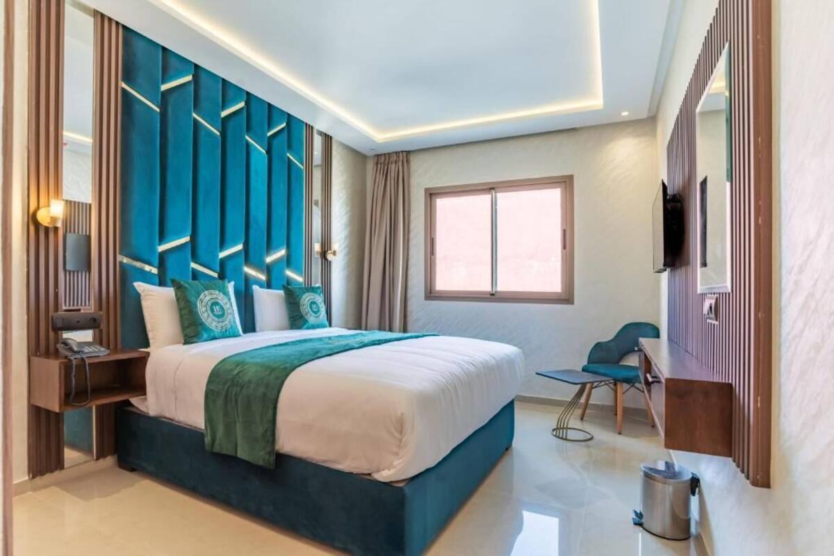 A modern hotel room with a large bed, a desk, a chair, and a TV.