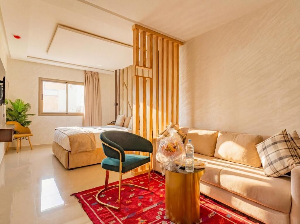 Een moderne hotelkamer met een bed, een bank, een stoel, een bijzettafeltje en een raam met gordijnen.