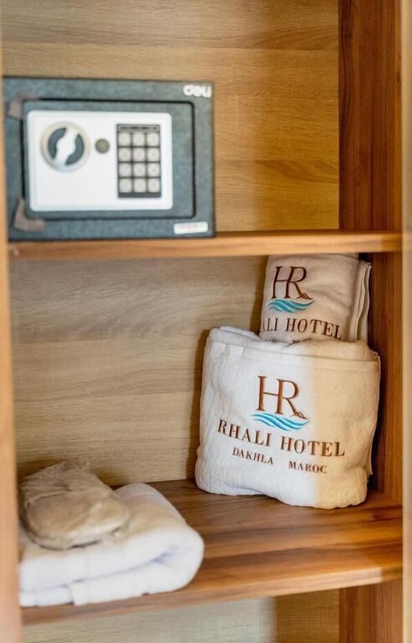 A wooden shelf with a radio, two towels with 'Rhali Hotel' branding, and a folded towel. - Hotel Rhali Dakhla (Dakhla)