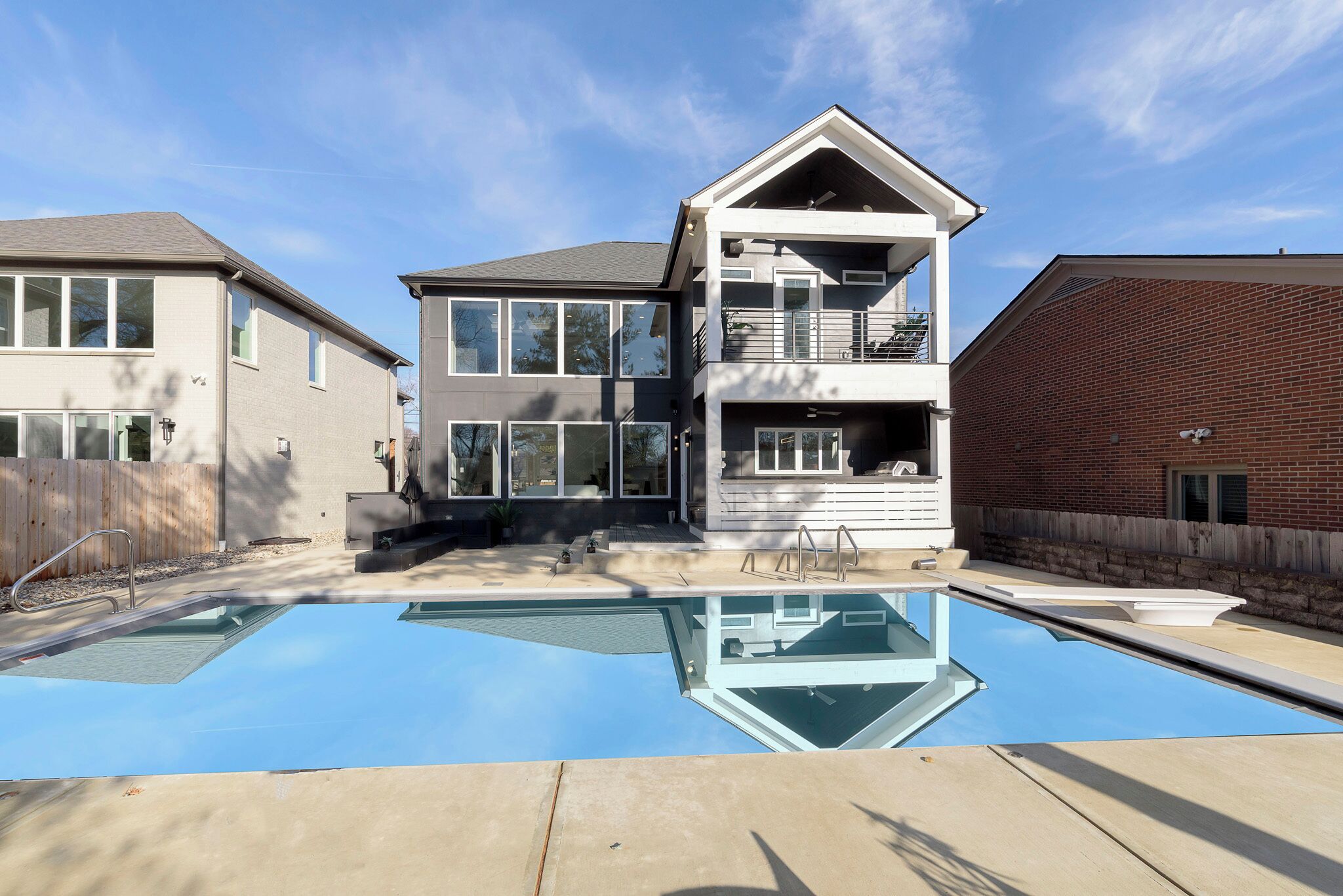 A two-story house with a swimming pool in front.