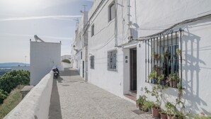 A narrow cobblestone street with a white building, potted plants, and a motorcycle parked on the side. - Apartment ‘Vacacional En Vejer’ (Vejer de la Frontera)