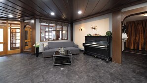 A modern living room with a piano, a sofa, and a coffee table. - Hotel Bären (Leimen)
