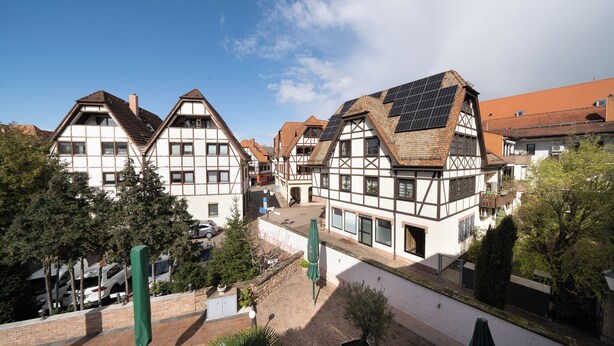 A traditional half-timbered building with a sloped roof, a visible chimney, and a solar panel installation. - Hotel Bären (Leimen)