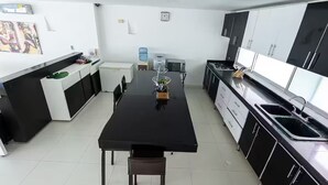 Een moderne keuken met zwart-wit keukenkastjes, een zwart aanrecht en een eethoek met een tafel en stoelen.