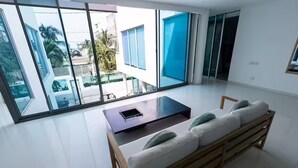Een moderne woonkamer met een glazen wand, een houten bank met kussens en een salontafel.