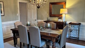Ein Esszimmer mit einer Chandelüster, einem Holztisch und vier Stühlen.