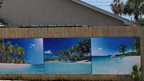A swimming pool with a wooden fence and a mural depicting a tropical beach scene. - Private Pool Oasis Less Than 2 Miles to PC Beach! (Panama City Beach)