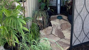A house entrance with a stone pathway, potted plants, a wooden door, and a metal gate. - Private Pool Oasis Less Than 2 Miles to PC Beach! (Panama City Beach)