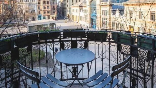 A terrace with a table and chairs, overlooking a cityscape with historic buildings. - Spicy Hostel (Budapest)