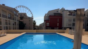 Une piscine avec un ciel bleu dégagé et une grande roue en arrière-plan.