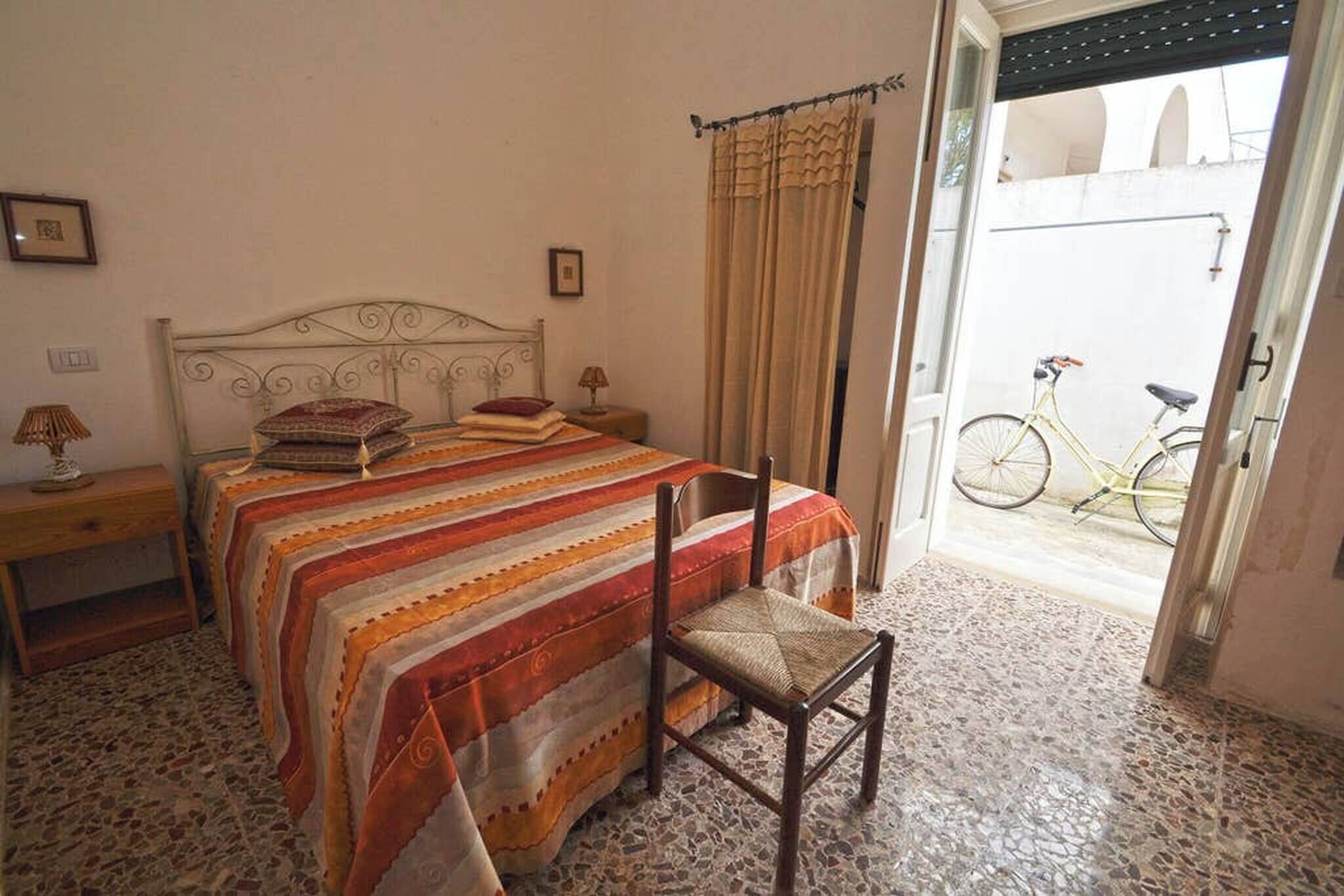 Ein Schlafzimmer mit einem Bett, einem Sessel, einer Lampe und einem Fahrrad im Hintergrund.